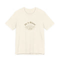 Beige t-shirt with 'He is Risen!' text and cross design on a white background