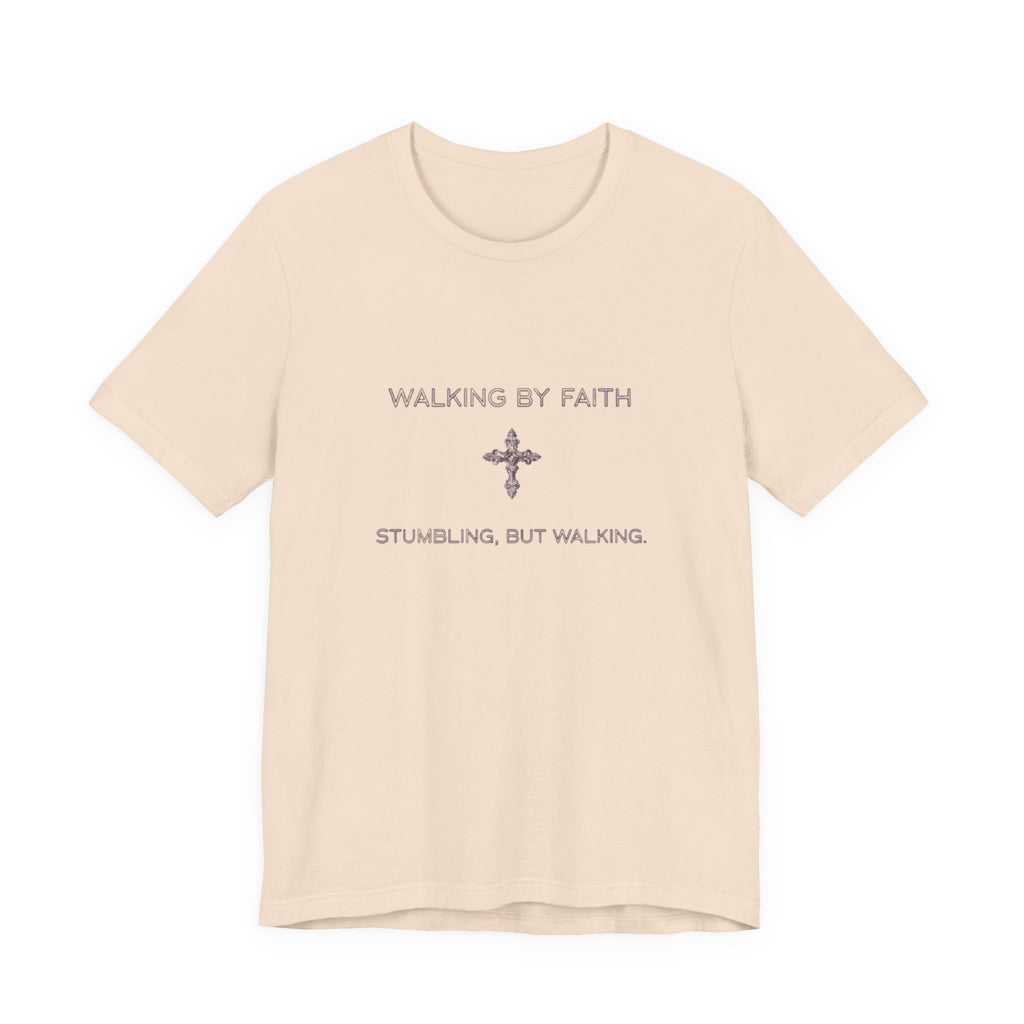 Beige t-shirt with text 'Walking by Faith, Stumbling, But Walking' on a white background
