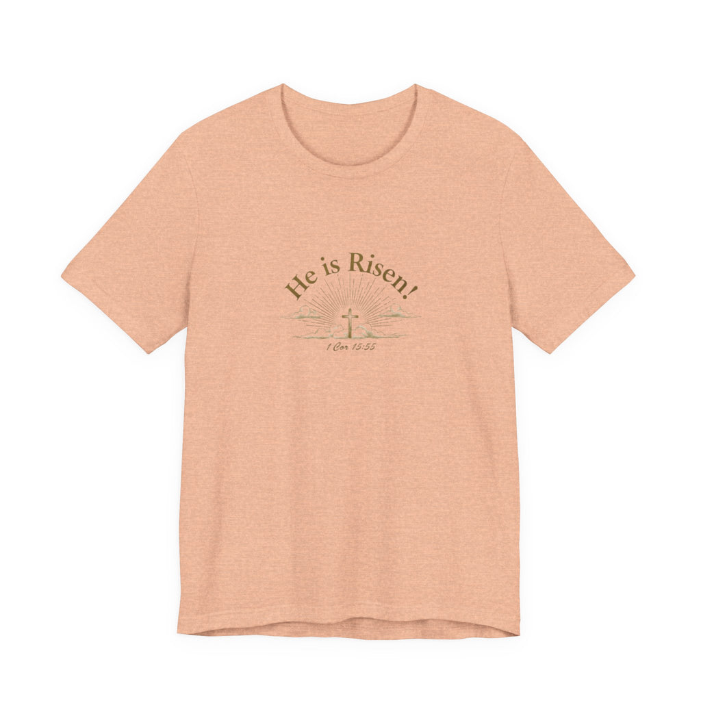 Peach t-shirt with 'He is Risen!' text and cross graphic on a white background