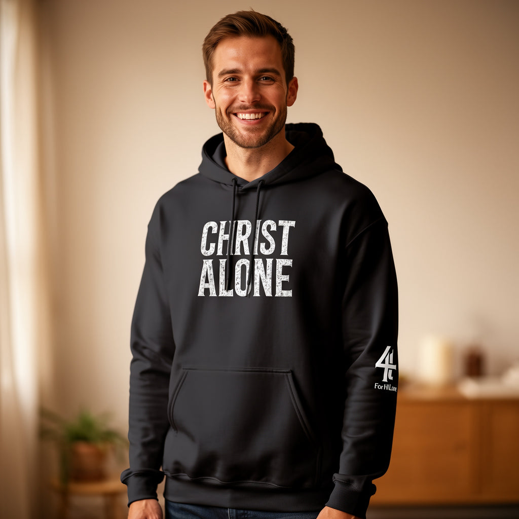 Man wearing a black hoodie with 'CHRIST ALONE' text in a home setting