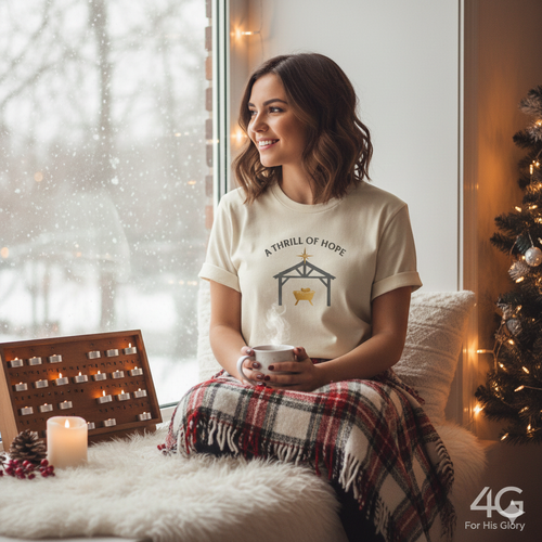 Woman sitting on a couch holding a mug, wearing a t-shirt with a Christmas design, in a cozy room with a Christmas tree and Advent calendar.