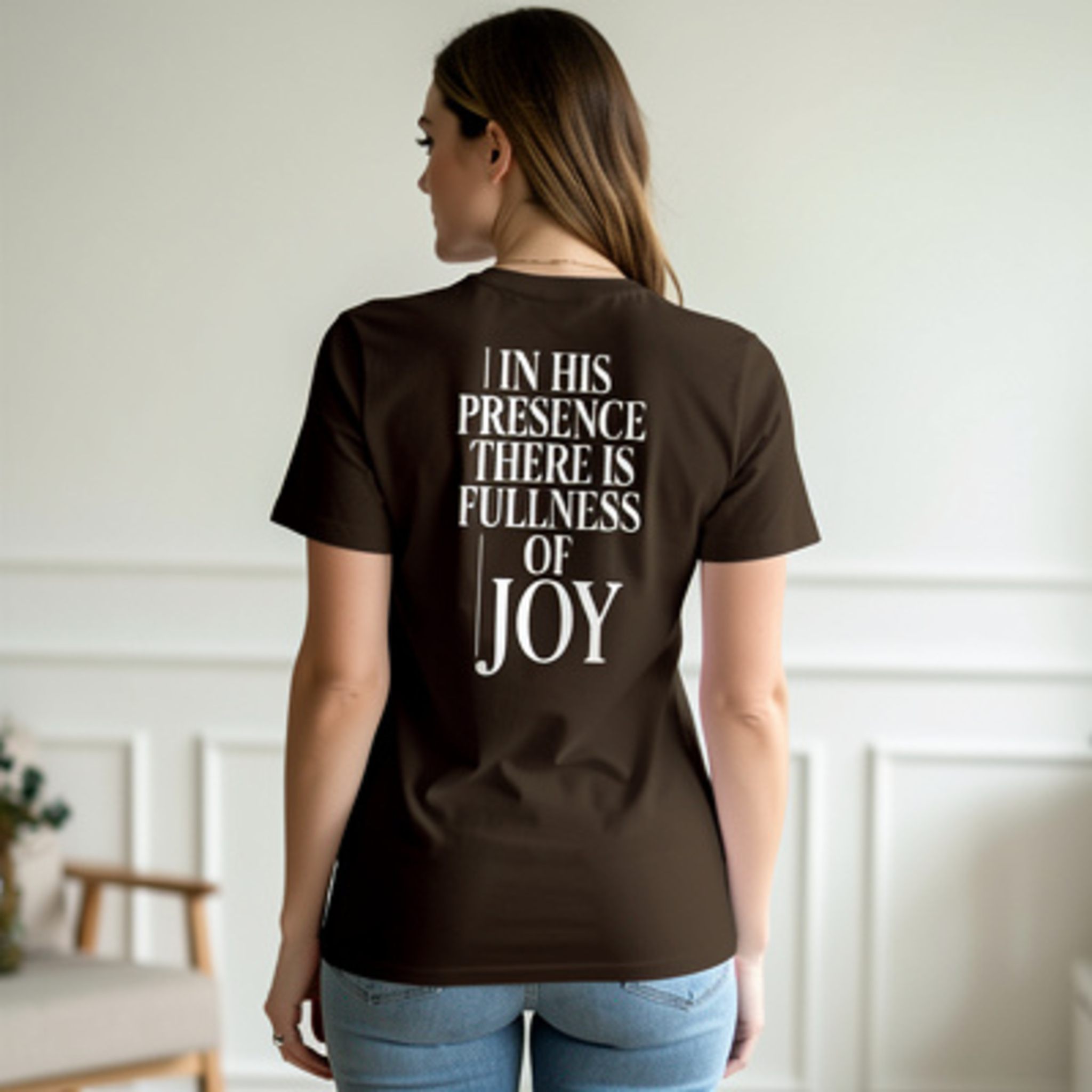 Person wearing a brown t-shirt with text on the back in a room.