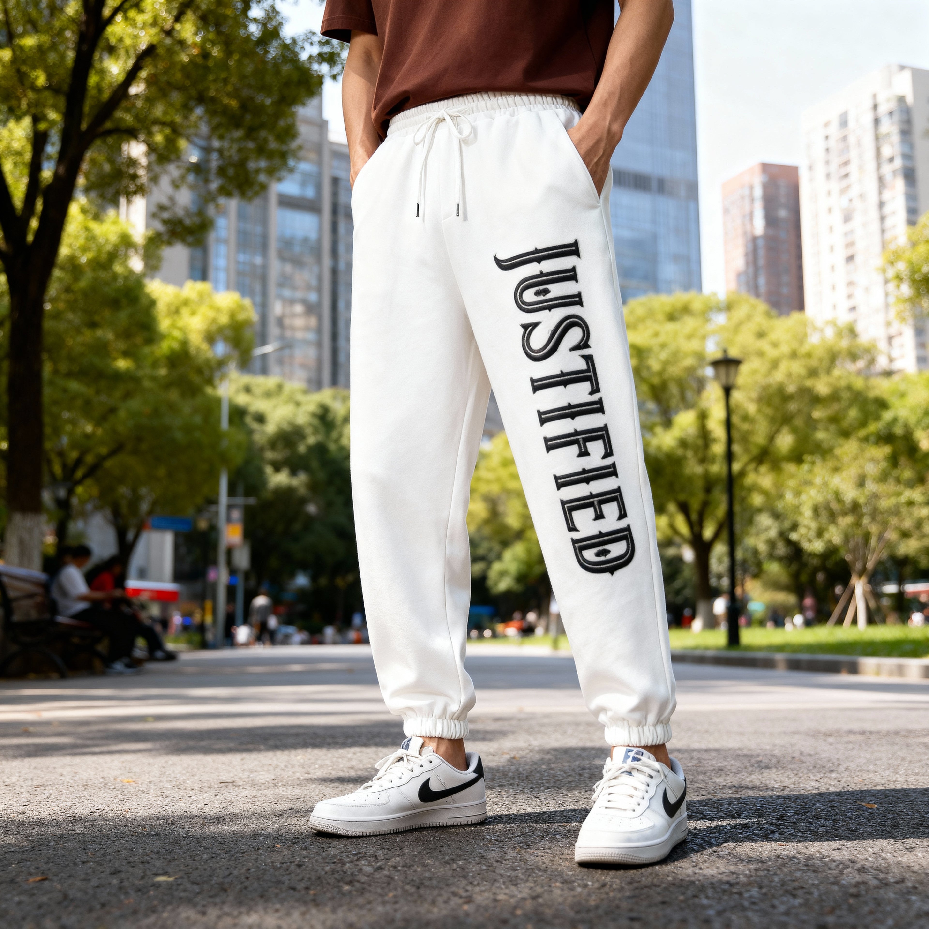 Person wearing white sweatpants with 'JUSTIFIED' text on a city street.