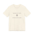 Beige t-shirt with text 'Walking by Faith, Stumbling, But Walking' on a white background