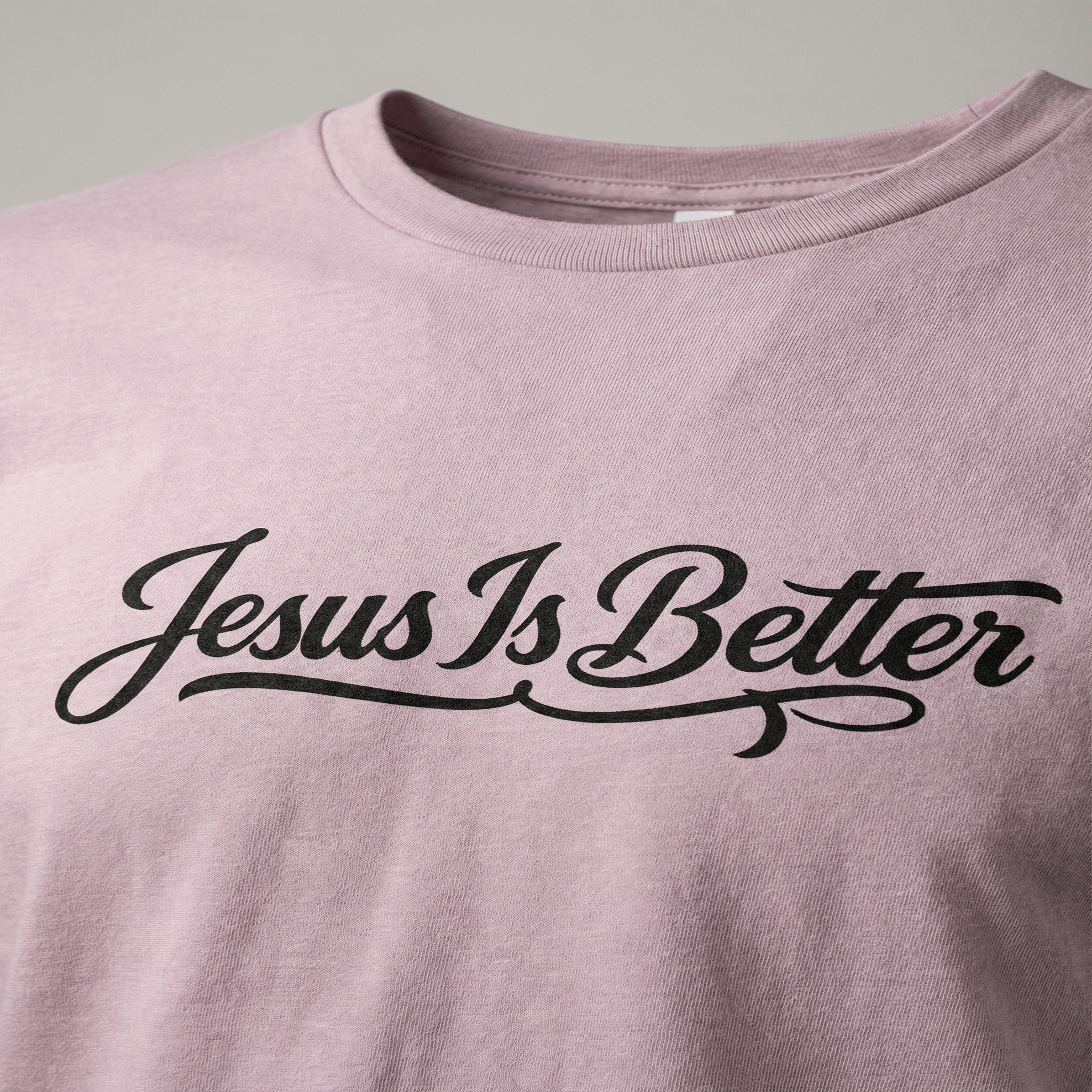 Pink t-shirt with 'Jesus Is Better' text on a plain background