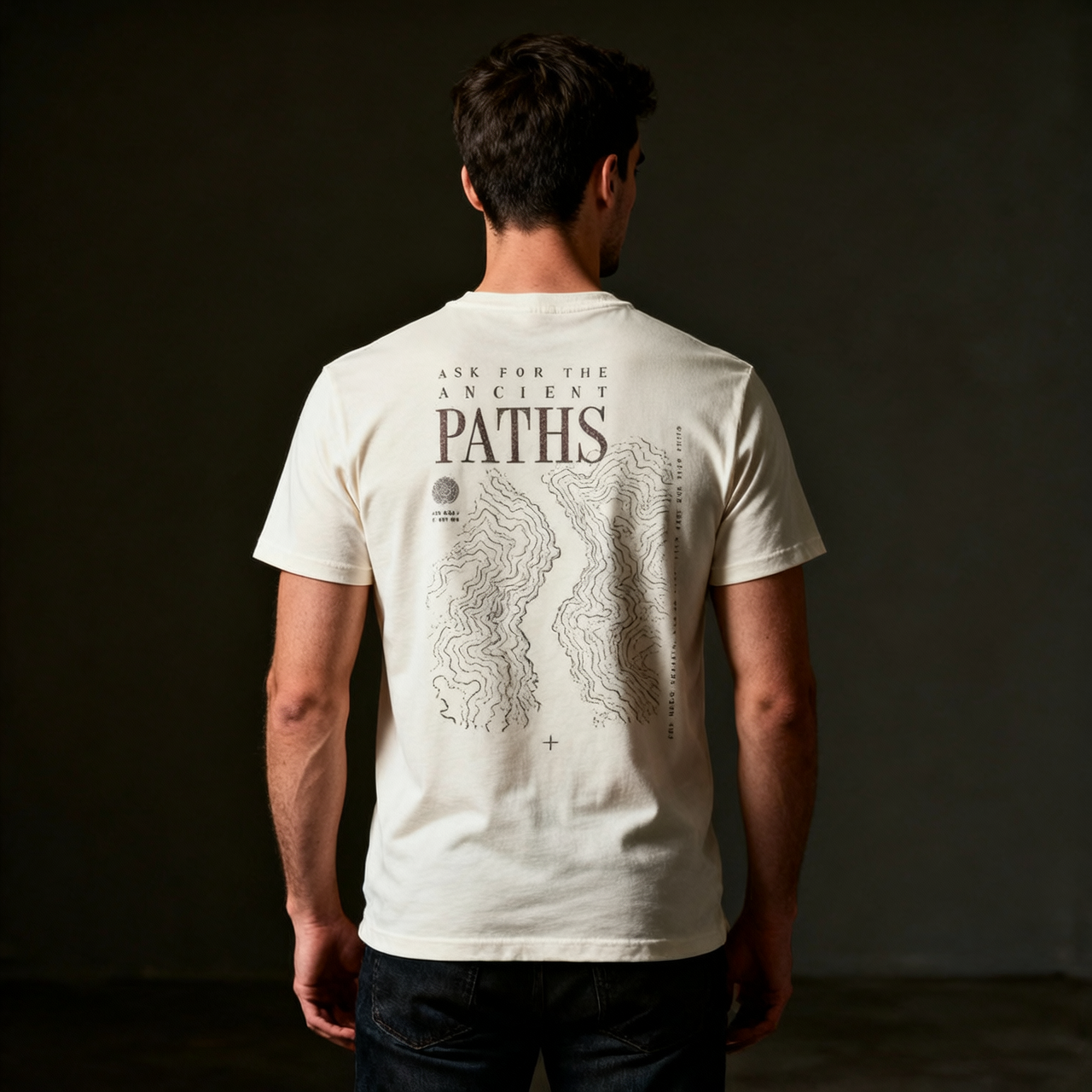 Man wearing a white t-shirt with 'Paths' design on the back against a dark background