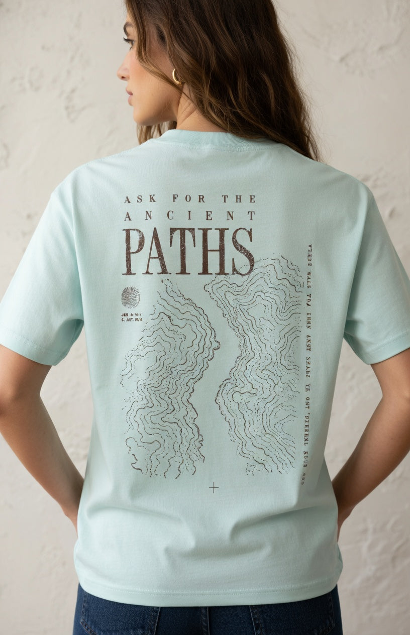 Person wearing a light blue t-shirt with 'Ask for the Ancient Paths' design on the back.