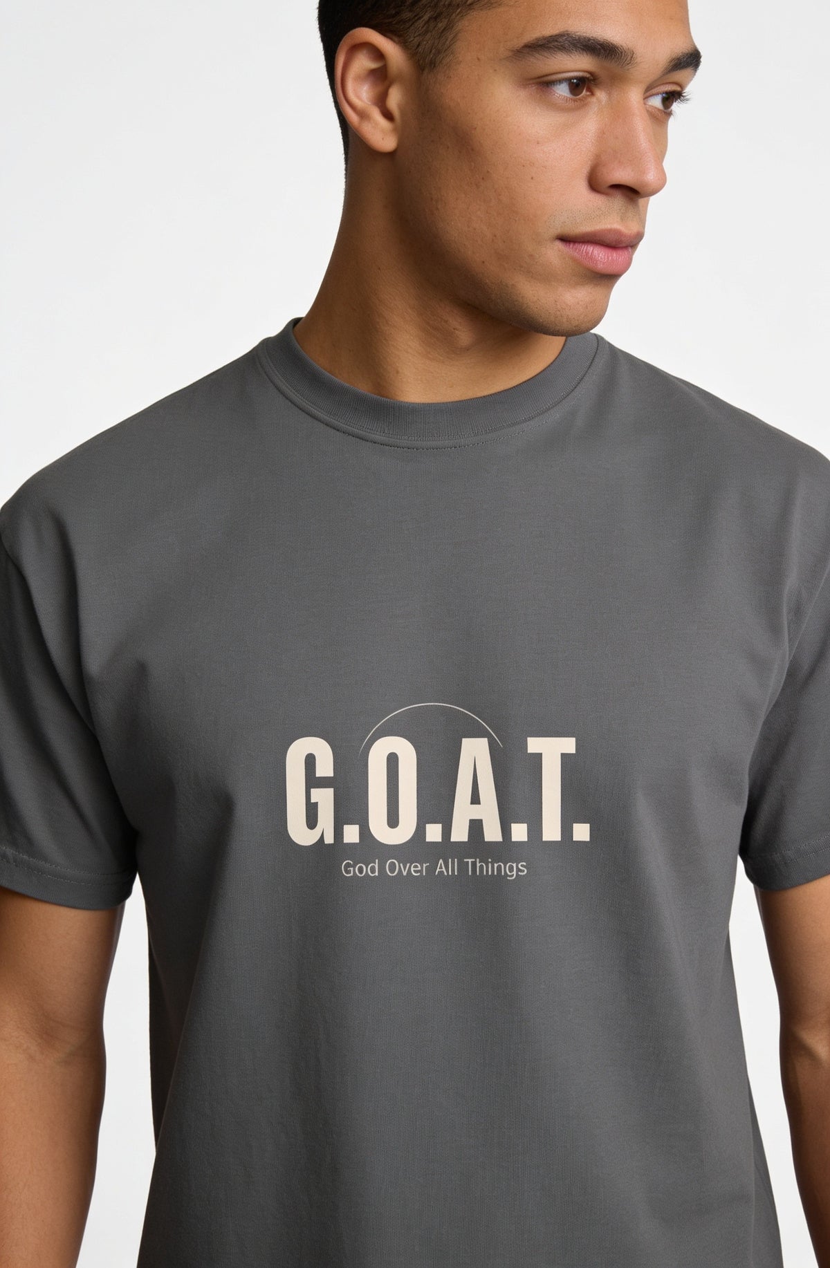 A man wearing a dark gray crewneck t-shirt with 'G.O.A.T.