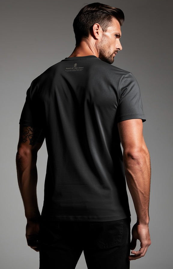 A man wearing a black short-sleeve athletic t-shirt, shown from the back and side against a neutral gray studio background.