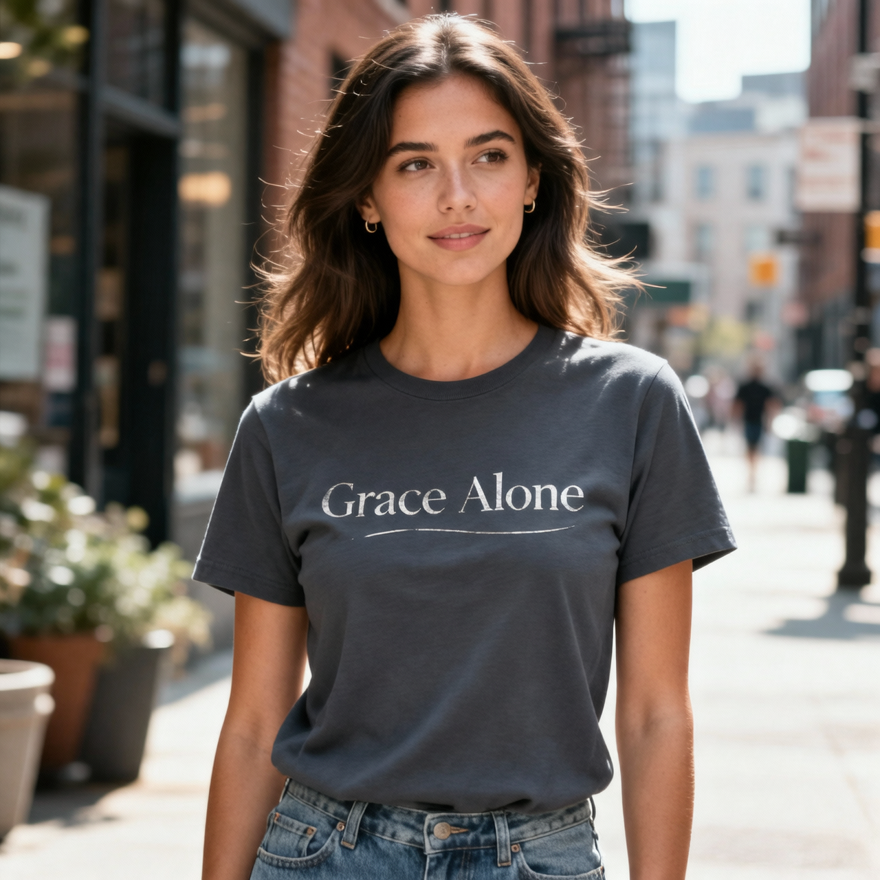 Woman wearing a t-shirt with 'Grace Alone' on a city street