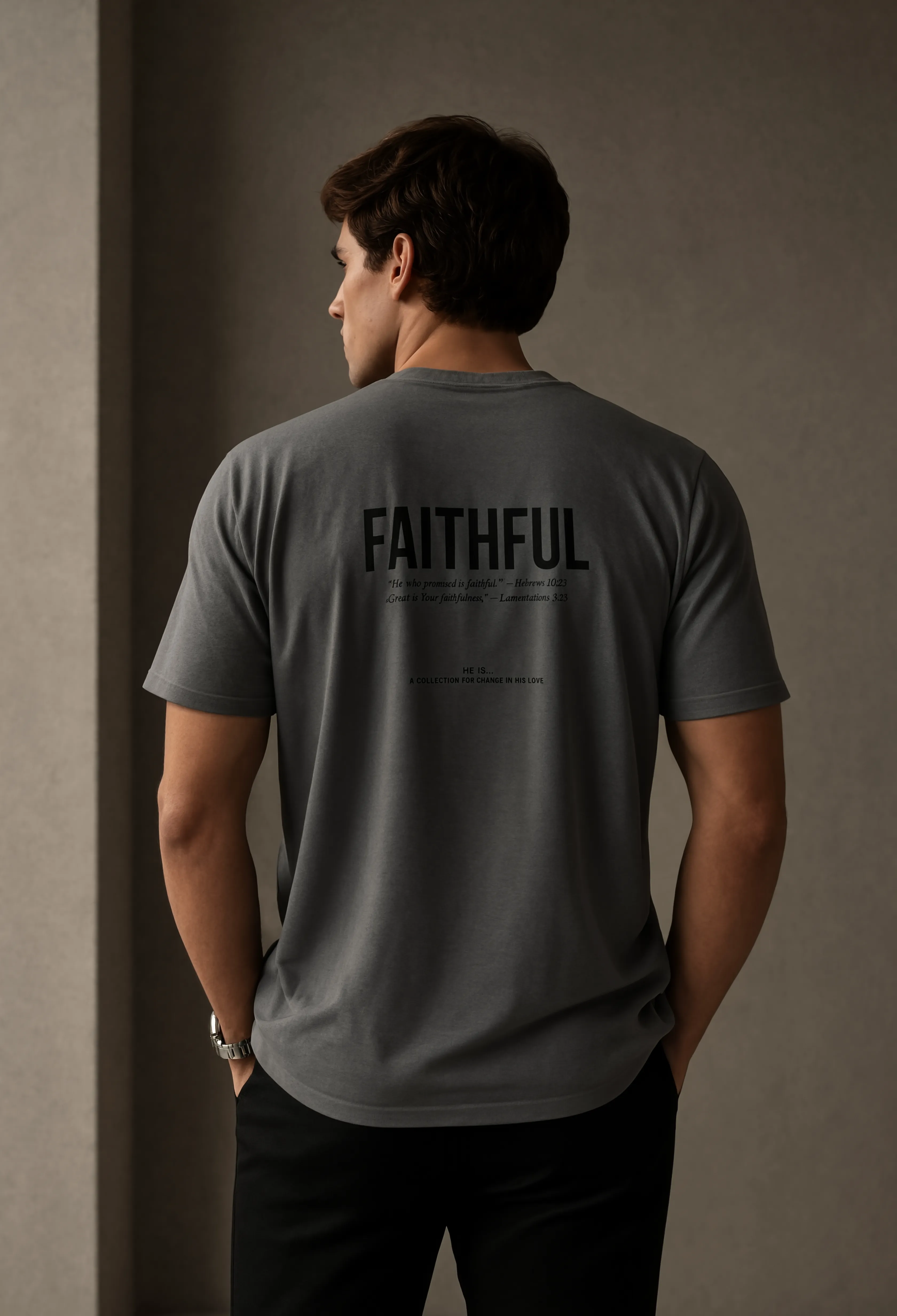 A man viewed from behind wearing a dark gray t-shirt with 'FAITHFUL' printed in black across the back, set against a neutral, warm-toned indoor background.