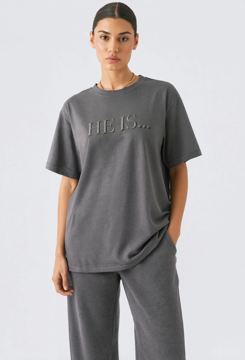 Female in editorial style mockup wearing He Is... shirt against white background.