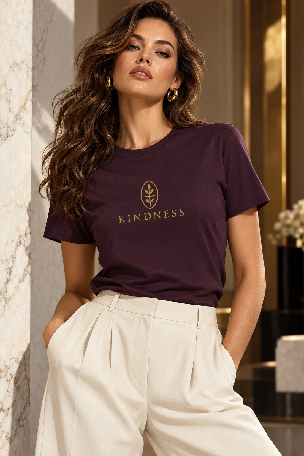 Woman wearing plum tshirt with Kindness next to marble wall.