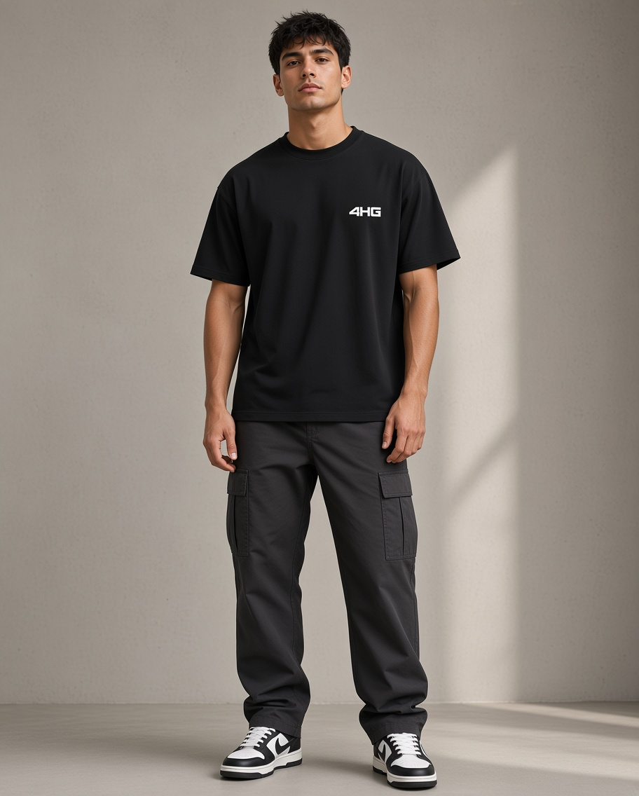 A man modeling a black short-sleeve t-shirt with a small white '4HG' logo on the left chest, paired with dark gray cargo pants and black-and-white sneakers, standing against a neutral beige studio backdrop.