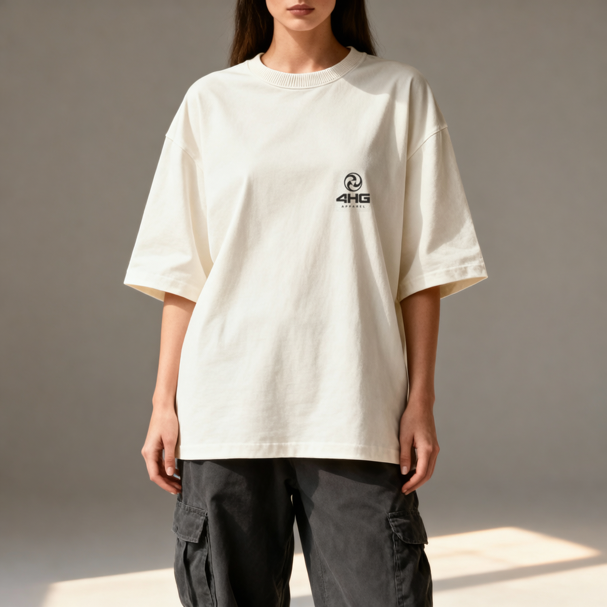 A model wearing an oversized off-white t-shirt with a small black '4HKG' logo on the left chest, paired with dark gray cargo pants, set against a neutral gray background.
