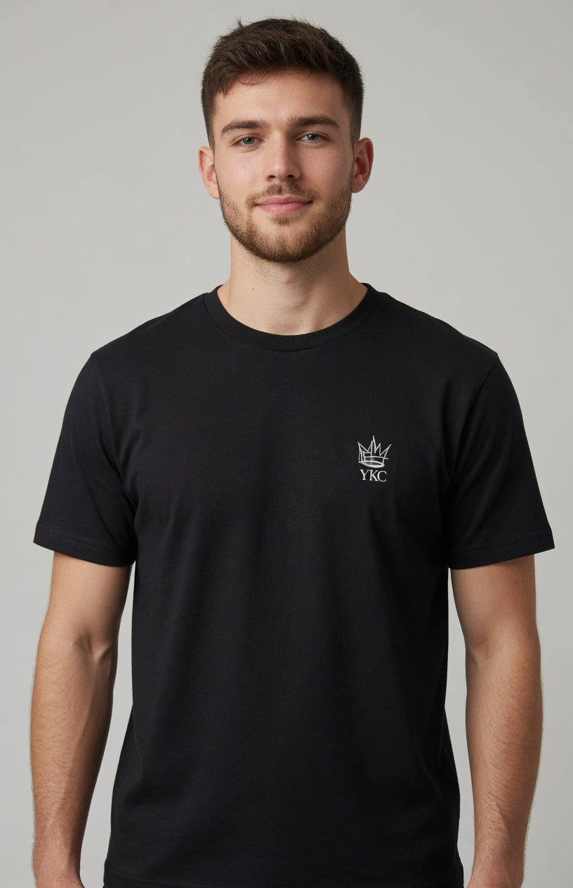Young adult wearing black t-shirt with YKC logo on left chest.