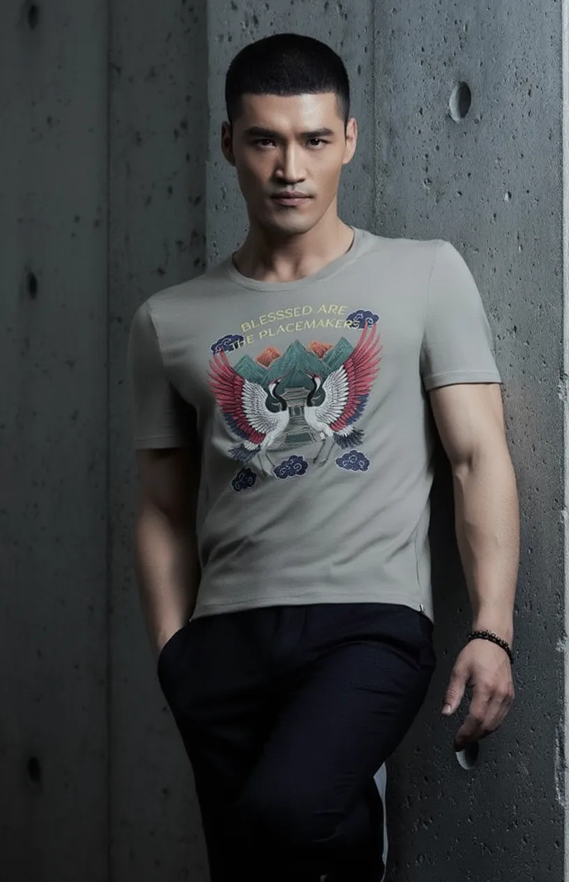 Man wearing a gray t-shirt with a graphic design against a concrete wall.