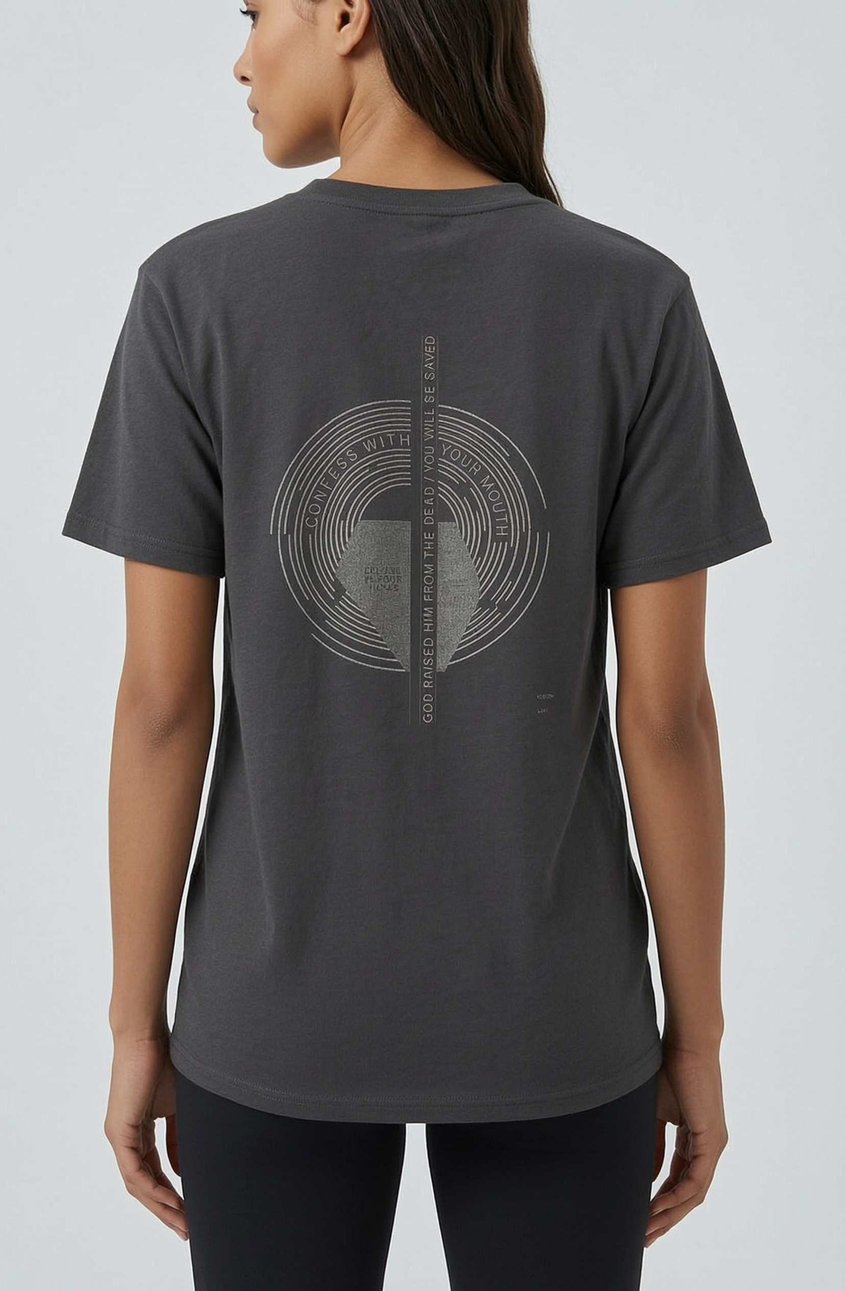 Person wearing a dark gray t-shirt with a circular design on the back against a light gray background