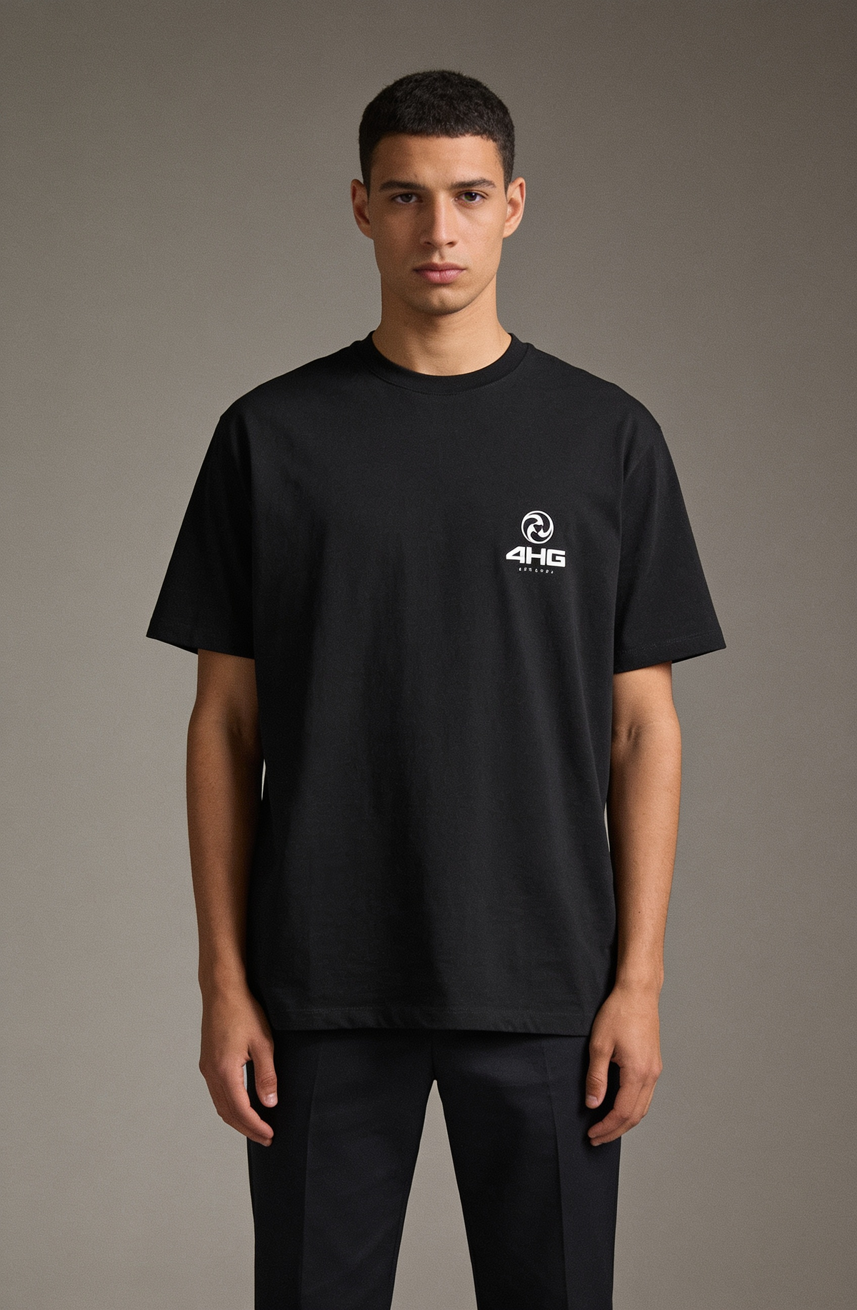A man wearing a black short-sleeve crewneck t-shirt with a small white 4H46 logo on the left chest, paired with black trousers, standing against a neutral gray studio background.