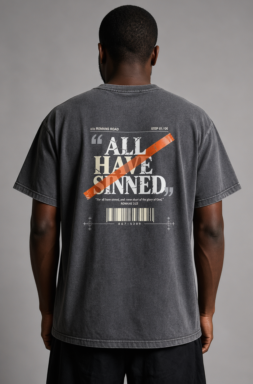 A man viewed from behind wearing a dark gray mineral-washed t-shirt with a graphic print on the back. The graphic features the quote 'ALL HAVE SINNED' in white text, crossed out with an orange diagonal line, and a barcode design below.
