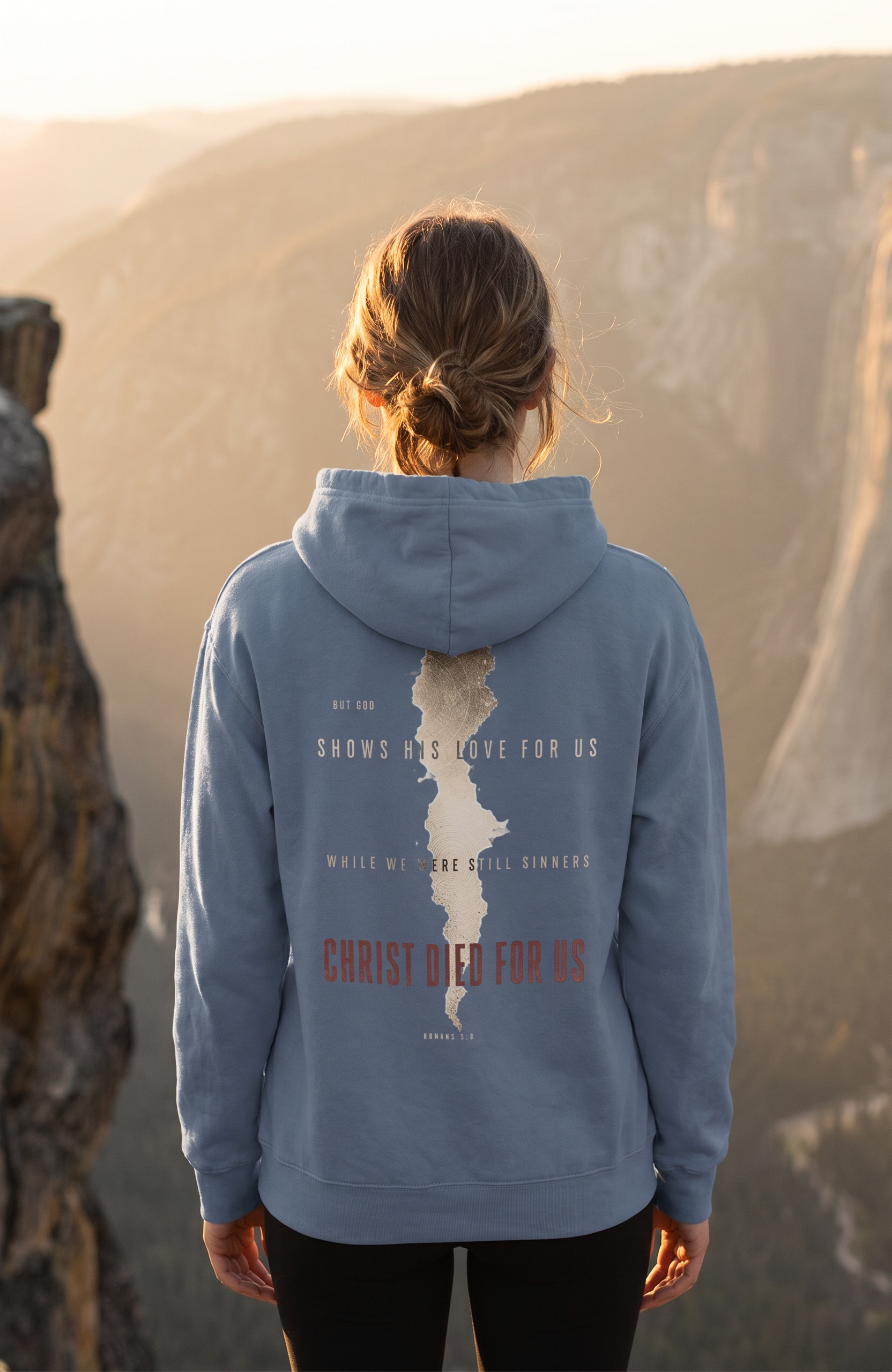 Person wearing a blue hoodie with a mountain design and text, standing in a desert landscape.